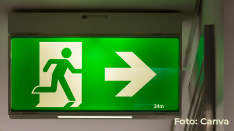 Grün leuchtendes Notausgang-Schild mit laufender Figur und Pfeil